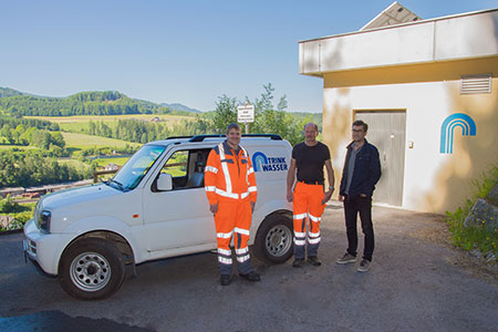 Drei Personen mit Auto stehen vor dem Wasserwerk